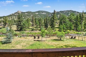 A view of a mountainous landscape with a wooden deck in the foreground.