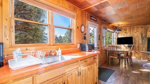 A wooden cabin interior with a kitchen area featuring a sink, microwave, and dining table.