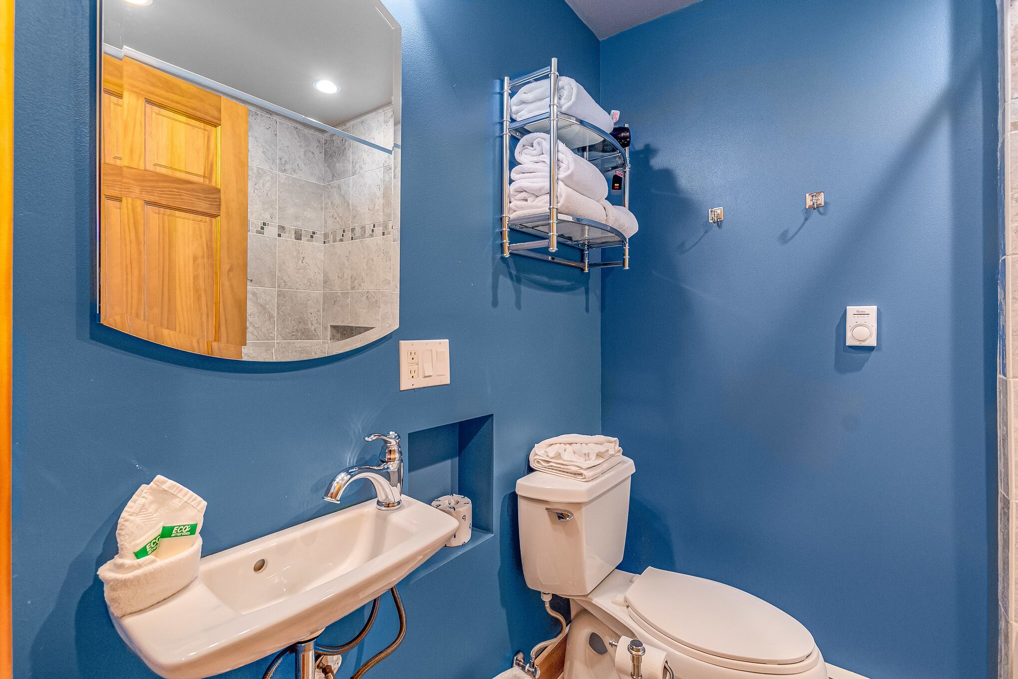 Une salle de bain avec un mur bleu, une porte en bois, un lavabo, des toilettes et un porte-serviettes.