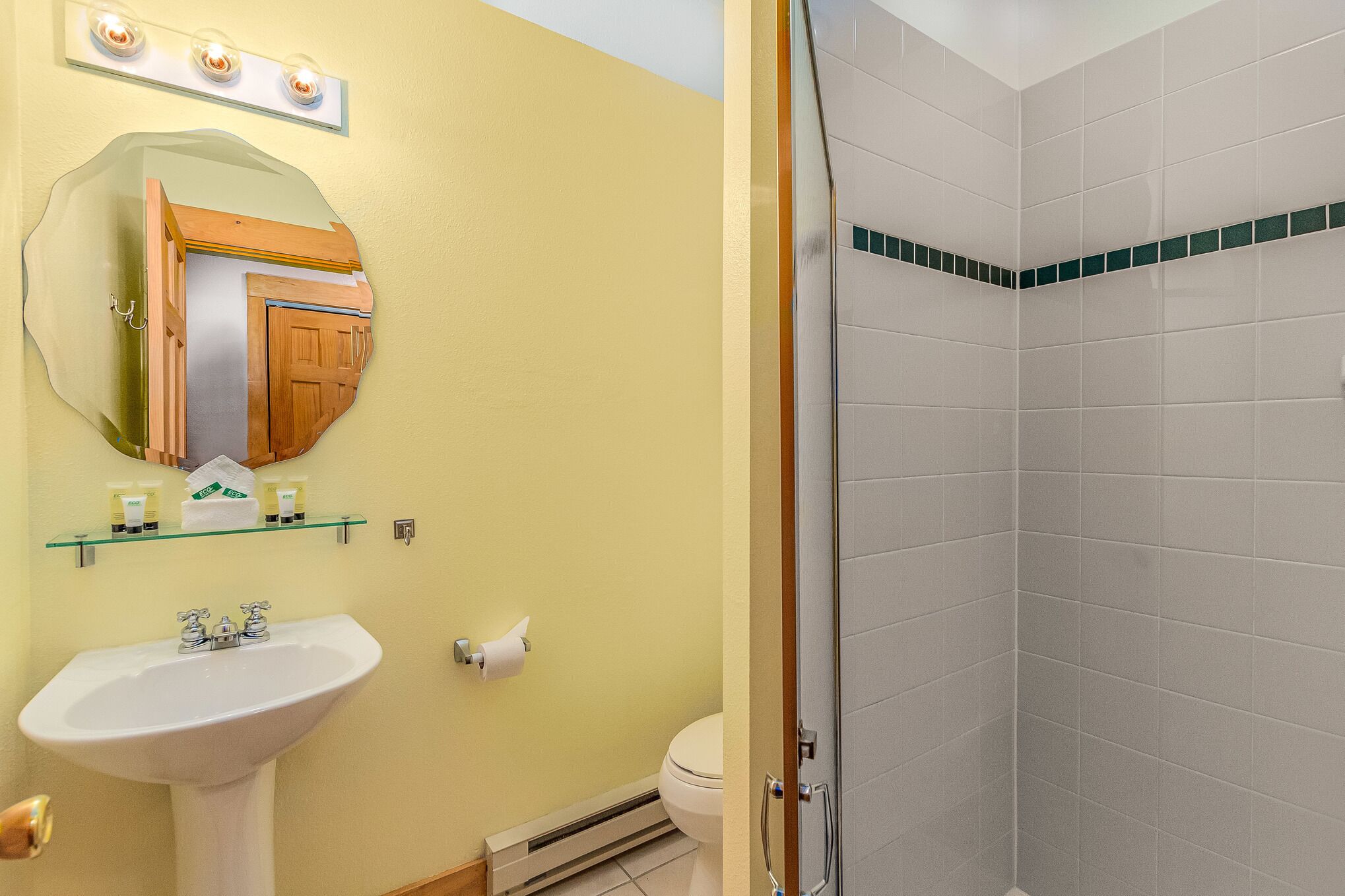 Une salle de bain équipée d’un lavabo, d’un miroir, de toilettes et d’une douche.