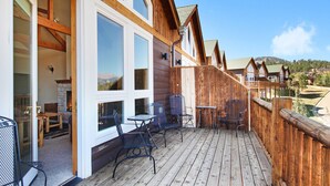 Una terraza de madera con mobiliario exterior y vistas a un paisaje montañoso.