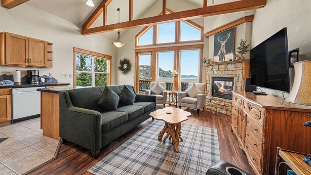 A cozy living area with a sofa, a fireplace, a television, and a stone fireplace surround.
