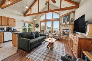 A cozy living area with a sofa, a fireplace, a television, and a stone fireplace surround.