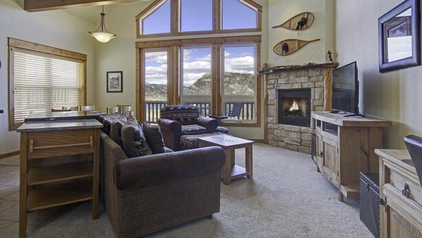 A spacious living room with a fireplace, large windows, a pool table, and a cozy seating area.