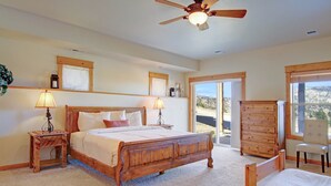 A bedroom with a wooden bed, two bedside tables with lamps, a wooden dresser, and a chair.
