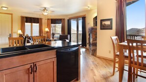 A kitchen with wooden cabinets, a dishwasher, and a dining area with a table and chairs.