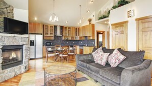 A modern living room with a fireplace, grey sofa, and a dining area with wooden chairs.