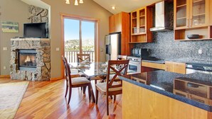 A modern kitchen with a stone fireplace, wooden cabinets, and a large island.