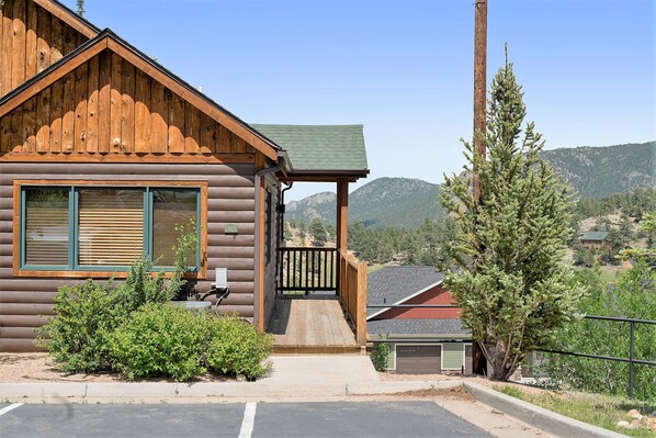 A log cabin with a porch, a garage, and a view of mountains.