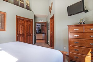 Un dormitorio con una cama grande, un armario de madera y un televisor montado.