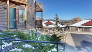 Une cabane en rondins avec un balcon, un escalier et une vue sur les montagnes.