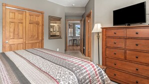 Une chambre à coucher avec un grand lit, une armoire en bois et un téléviseur.