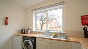 A compact kitchen with a washing machine, a toaster, a sink, and a fire extinguisher. - Stunning 2-bed Apartment in Washington (Washington)
