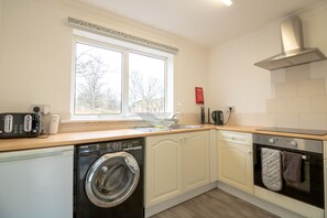 A compact kitchen with a washing machine, oven, and a window providing natural light. - Stunning 2-bed Apartment in Washington (Washington)