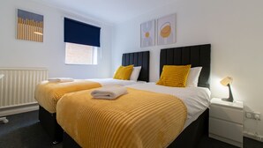 A hotel room with two beds, a nightstand with a lamp, and artwork on the walls. - Stunning 2-bed Apartment in Washington (Washington)