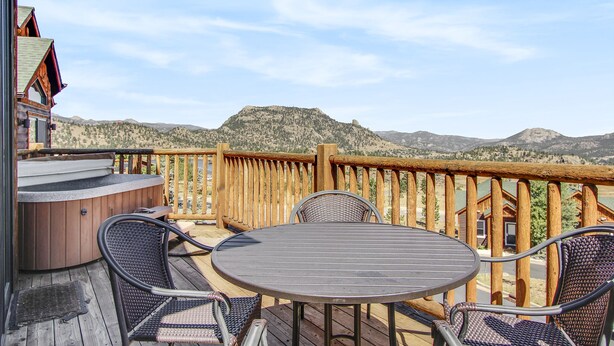A wooden deck with a hot tub, wicker chairs, and a table.