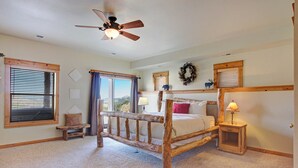 Une chambre à coucher avec un lit à baldaquin en bois, un ventilateur de plafond et une vue sur l’extérieur.