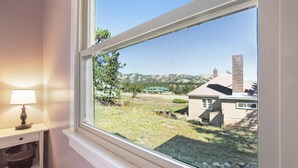 Ein Fenster mit Blick auf eine Wiese und ein Gebäude in der Ferne.
