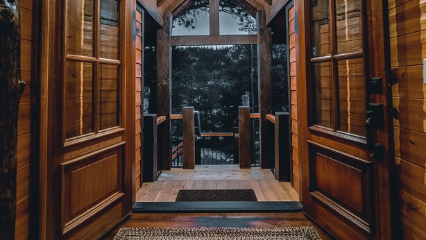 A wooden interior with a central wooden staircase leading to a balcony.