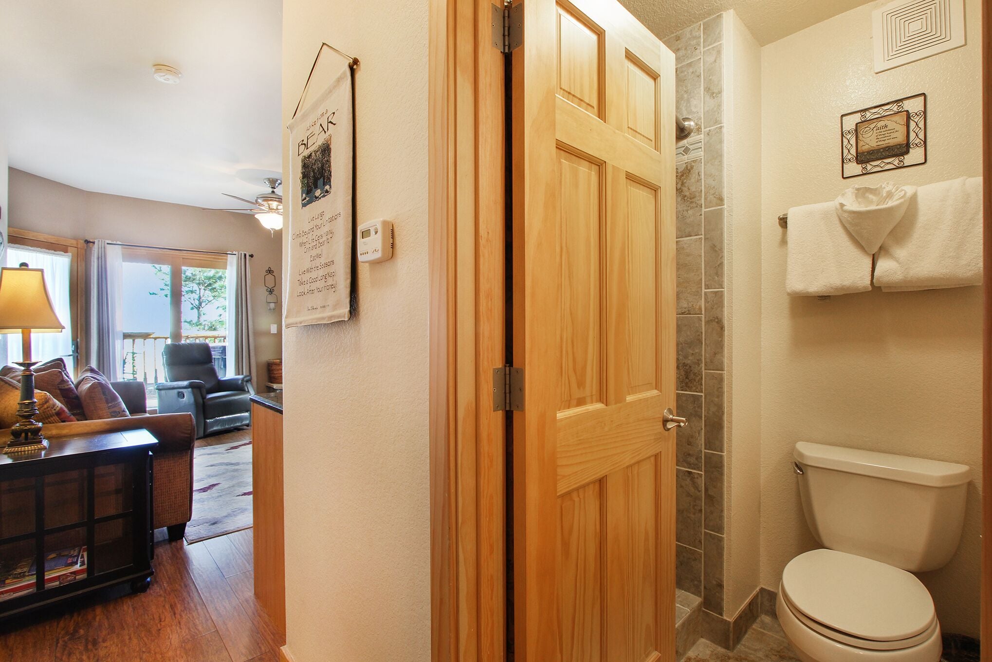 Puerta de madera que da a un baño con inodoro y perchero.