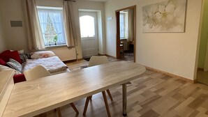 Une pièce spacieuse avec une grande table à manger en bois, un coin salon confortable avec un canapé et une grande fenêtre agrémentée de rideaux.
