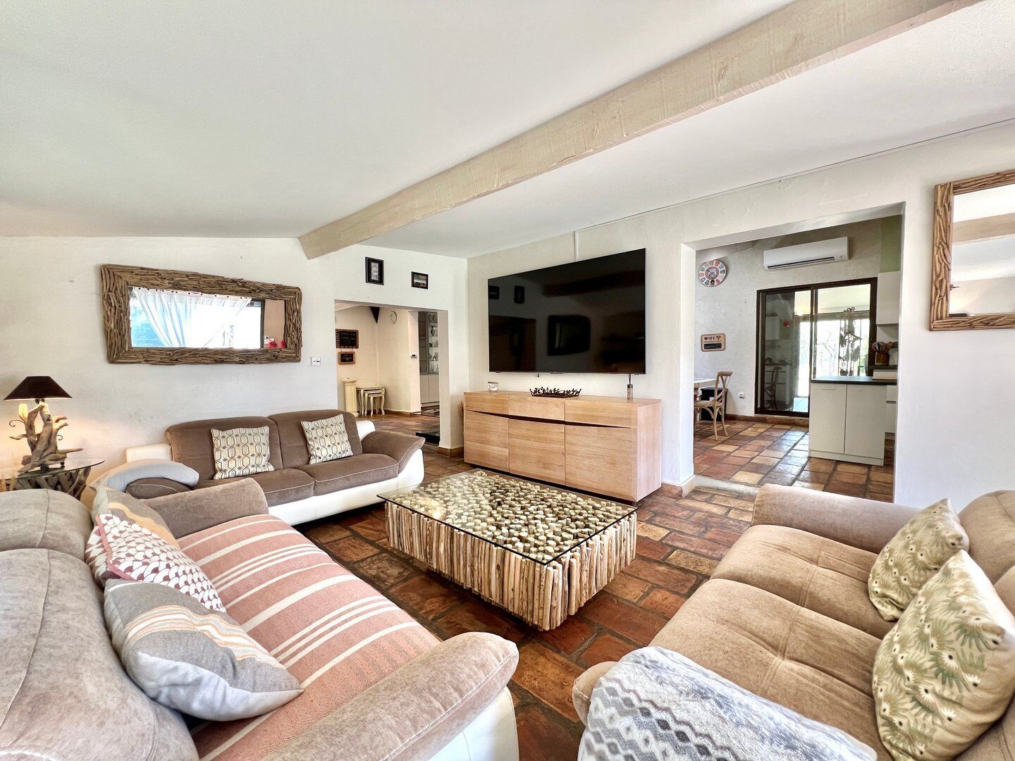 Amplia sala de estar con una televisión de pantalla plana grande, una mesa de centro de madera y un juego de sofás.