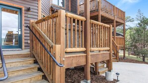 Un escalier en bois menant à une terrasse dotée de rampes, une porte avec une fenêtre et une plaque portant le numéro 27C.