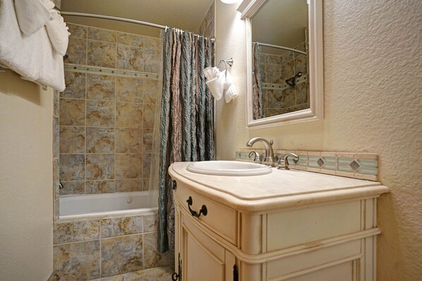 Un baño con bañera, lavamanos y espejo.