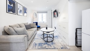 Un salon moderne avec un canapé, une table basse et des œuvres d’art accrochées au mur.