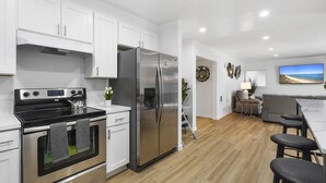 Una cocina moderna con electrodomésticos de acero inoxidable, armarios blancos y suelo de madera.