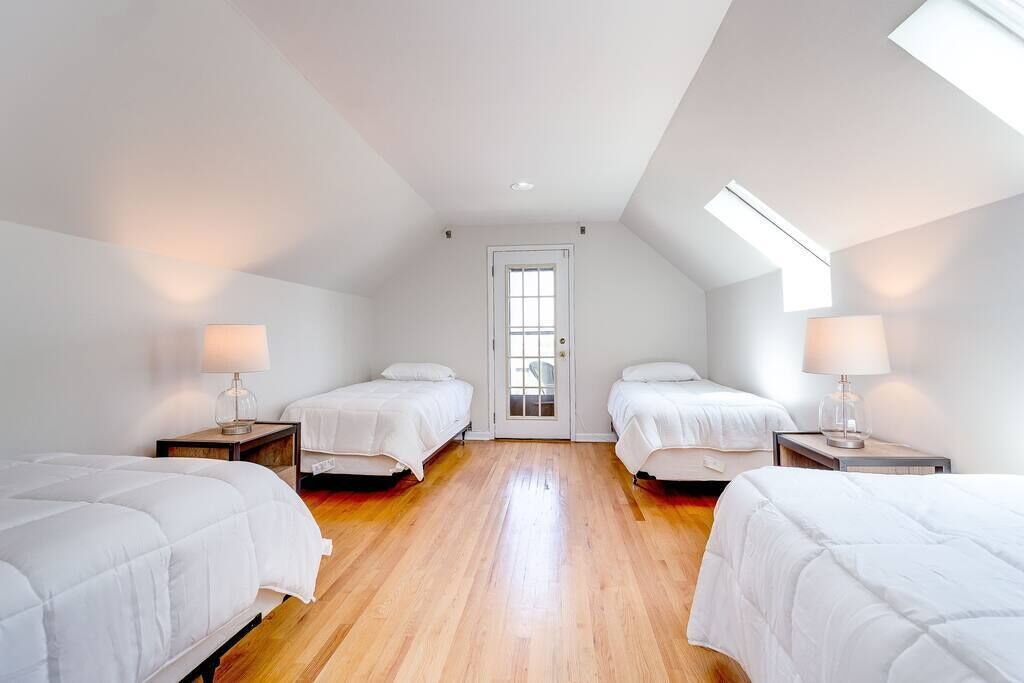 Een slaapkamer met drie bedden, houten vloeren en een dakraam.