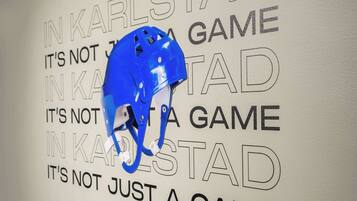 Ein blauer Helm hängt an der Wand, mit dem Text „IN KARLSBAD IST ES MEHR ALS NUR EIN SPIEL“.