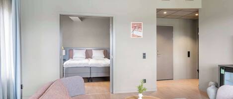 Una habitación de hotel moderna con una cama, un sofá, una mesita y una planta en maceta.