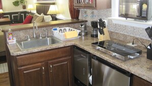 A modern kitchen with granite countertops, stainless steel appliances, and wooden cabinets. - Sailor's Cove Studio. (St. Augustine)