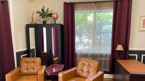A room with two leather armchairs, a small table, a globe on a cabinet, and a window with curtains. - Sailor's Cove Studio. (St. Augustine)