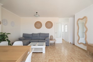 A living room with a grey sofa, a coffee table, a plant, and a large mirror. - V89B | Villa Sea Lights (Son Bou)