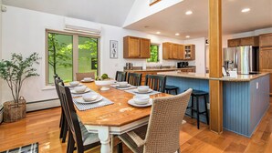 A spacious kitchen with wooden cabinets, a central island, and a dining area with a wooden table and chairs. - Cozy Cottage w/ Shared Neighborhood Lake Access (Traverse City)
