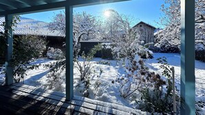 Ein überdachter Außenbereich mit Blick auf eine verschneite Landschaft und Gebäude.