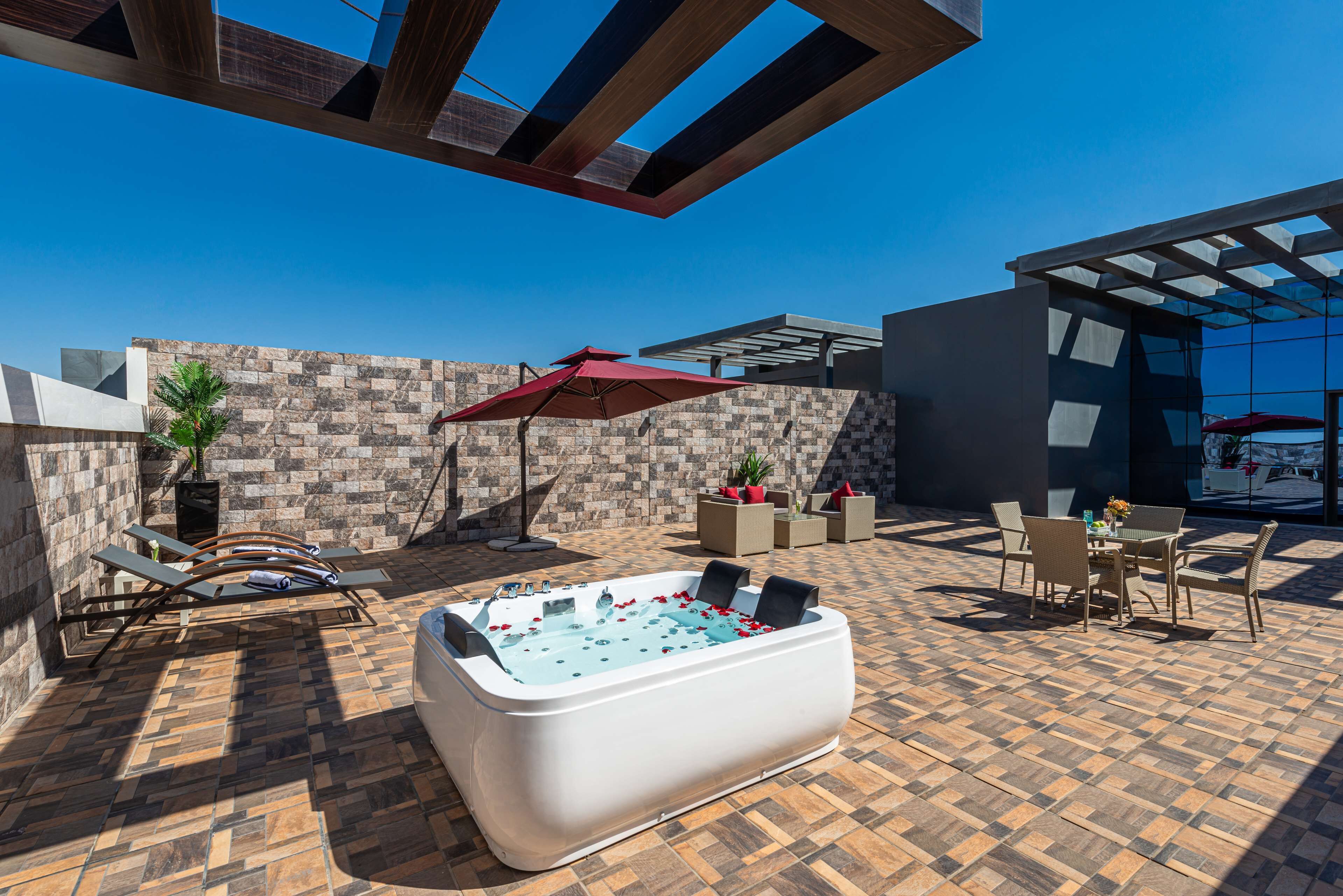 A rooftop patio with a hot tub, lounge chairs, and outdoor furniture.