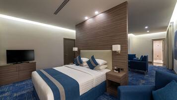 Una habitación de hotel con una cama grande, televisión, escritorio y zona de estar.