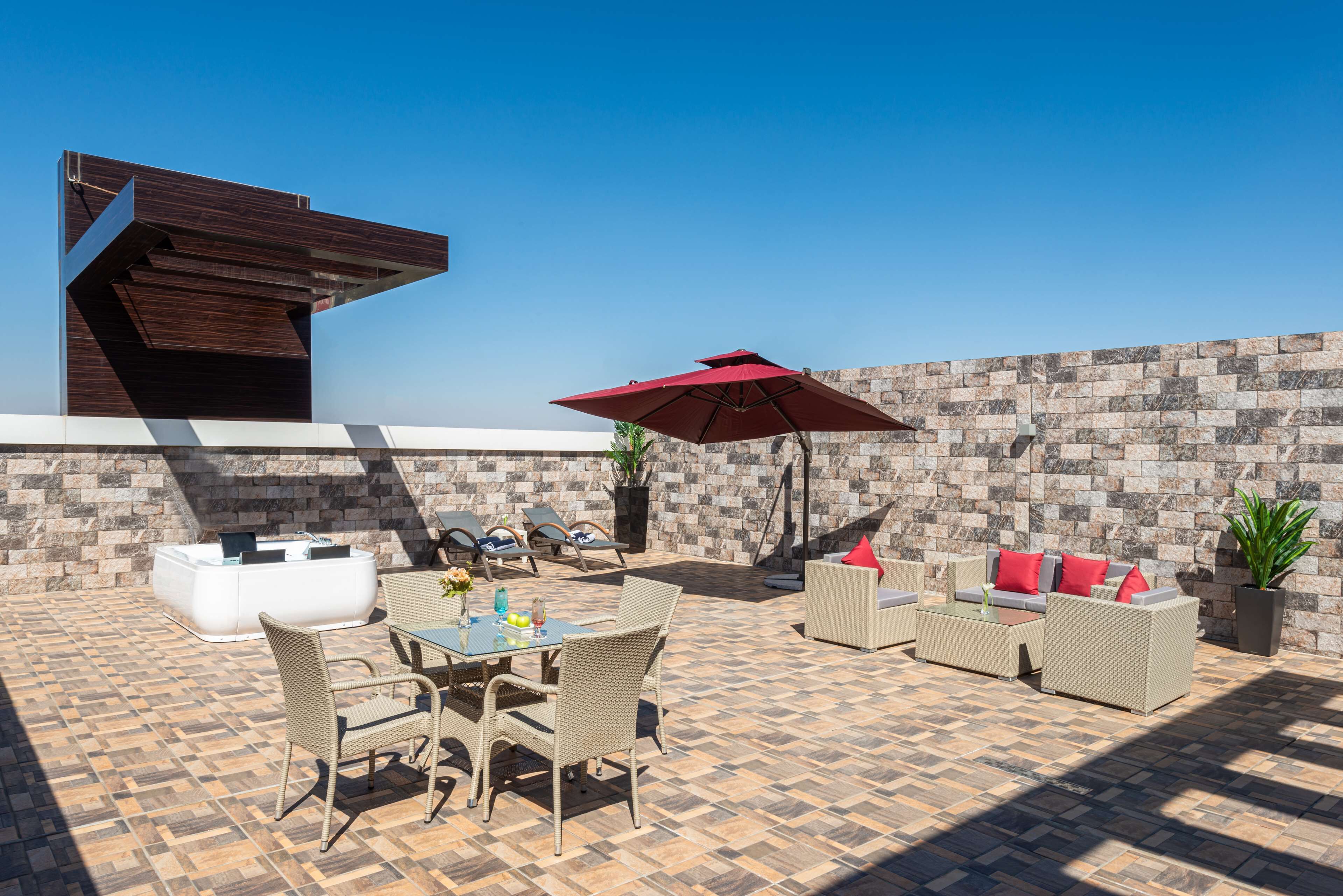 An outdoor patio with a stone wall, wicker furniture, and a modern building structure.