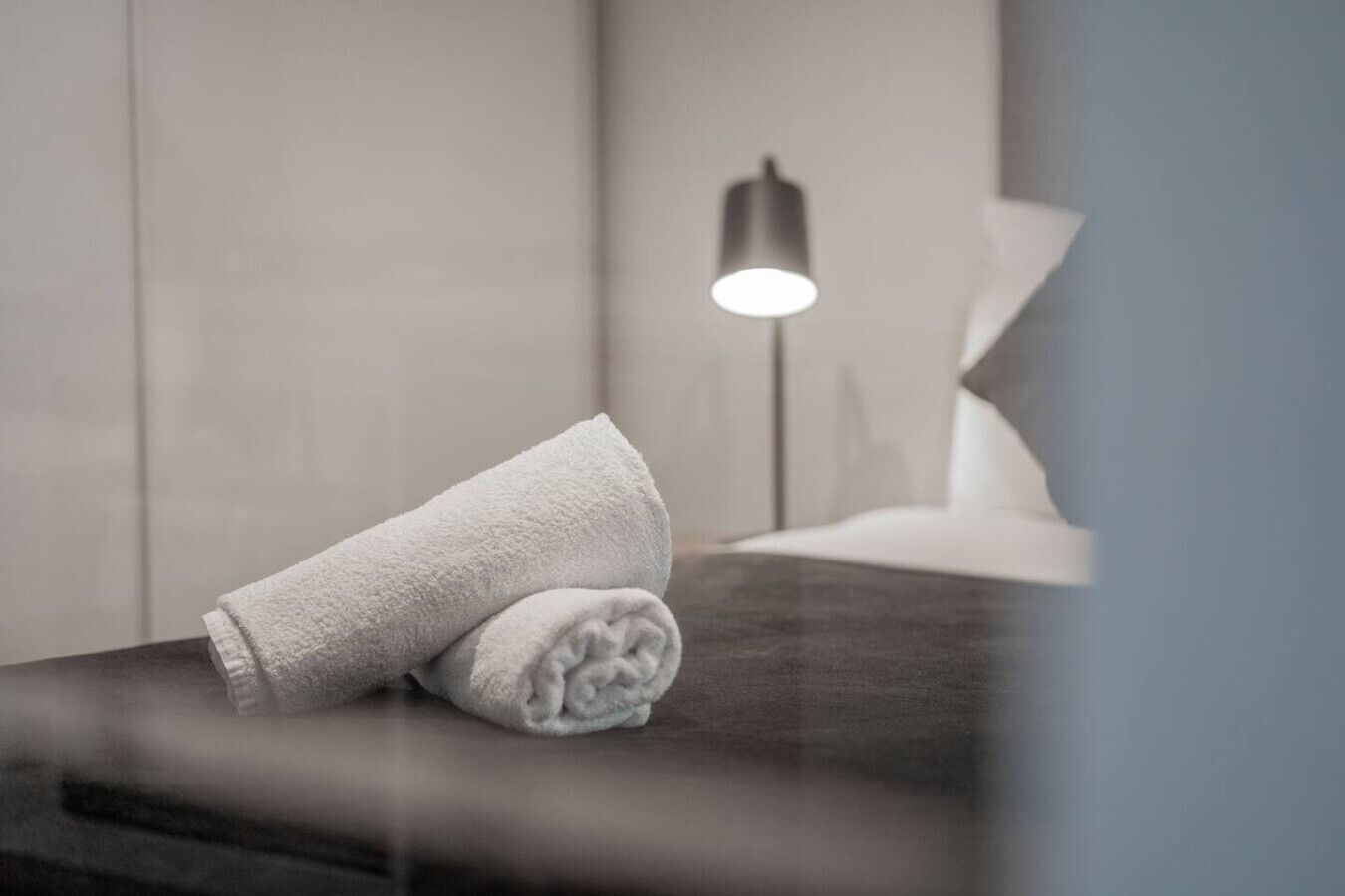 Una toalla blanca doblada cuidadosamente sobre una superficie de madera oscura en una habitación de hotel.