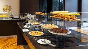 A buffet with various pastries, cakes, and beverages.