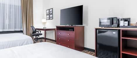 Habitación de hotel con dos camas, televisión, mini refrigerador, microondas y cafetera.