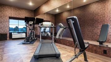 A gym with a treadmill, elliptical, and weight bench.