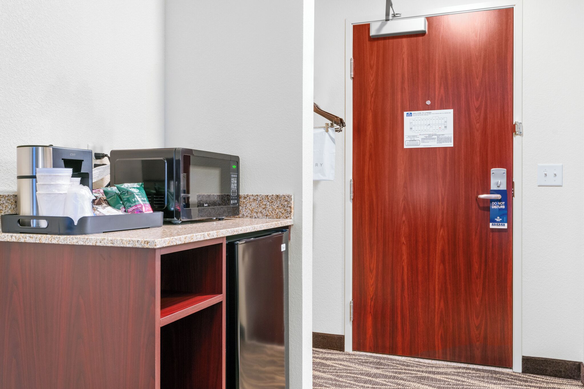 Una kitchenette equipada con microondas, cafetera y espacio para artículos de aseo.