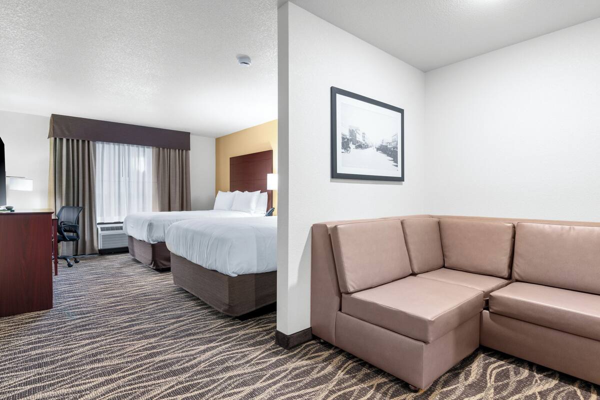 A hotel room with a bed, a sofa, a desk, and a chair.