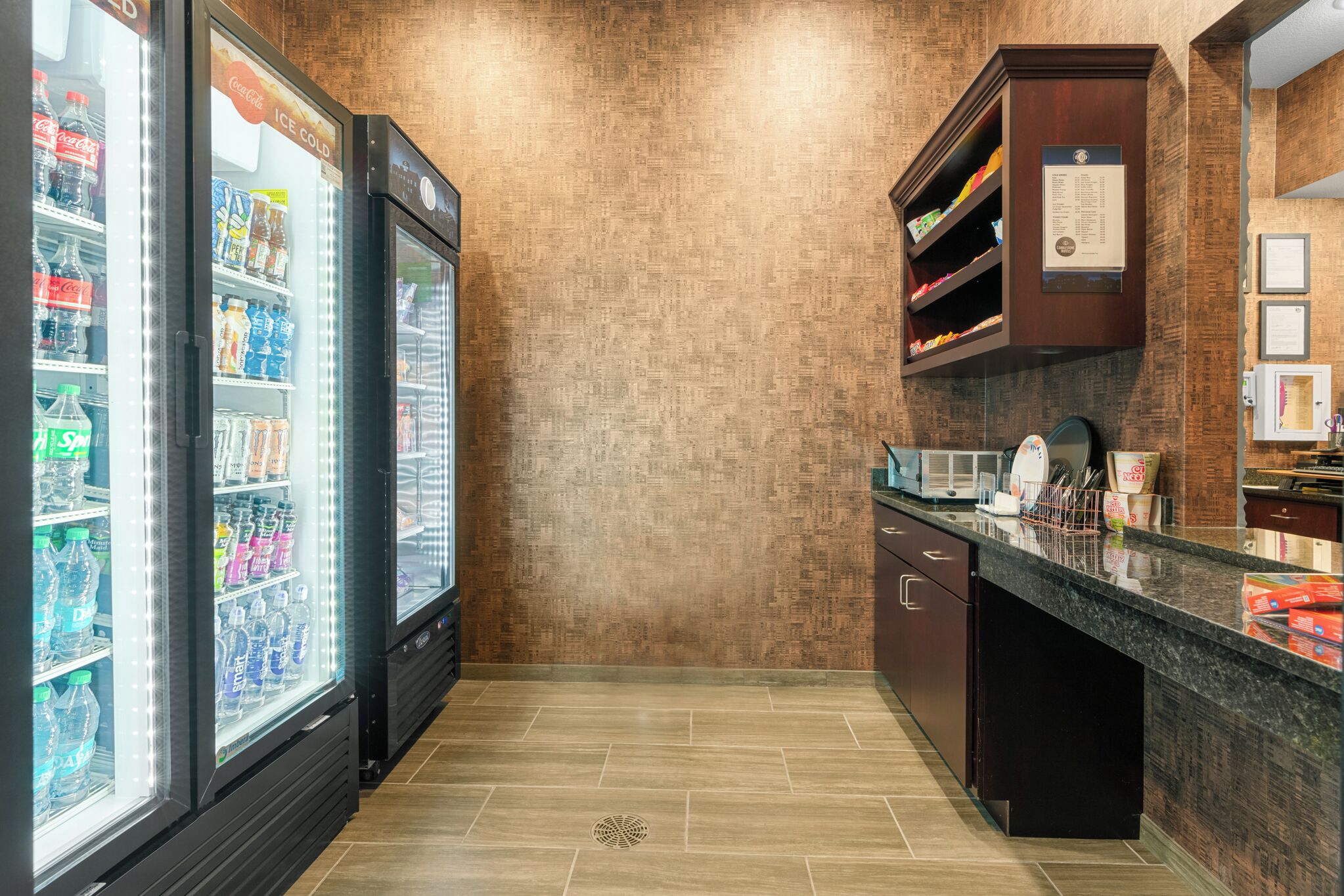 A kitchen with a granite countertop, a microwave, and a refrigerator stocked with beverages.