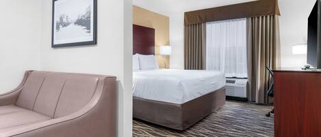 A hotel room with a bed, a sofa, a desk, and a framed picture on the wall.