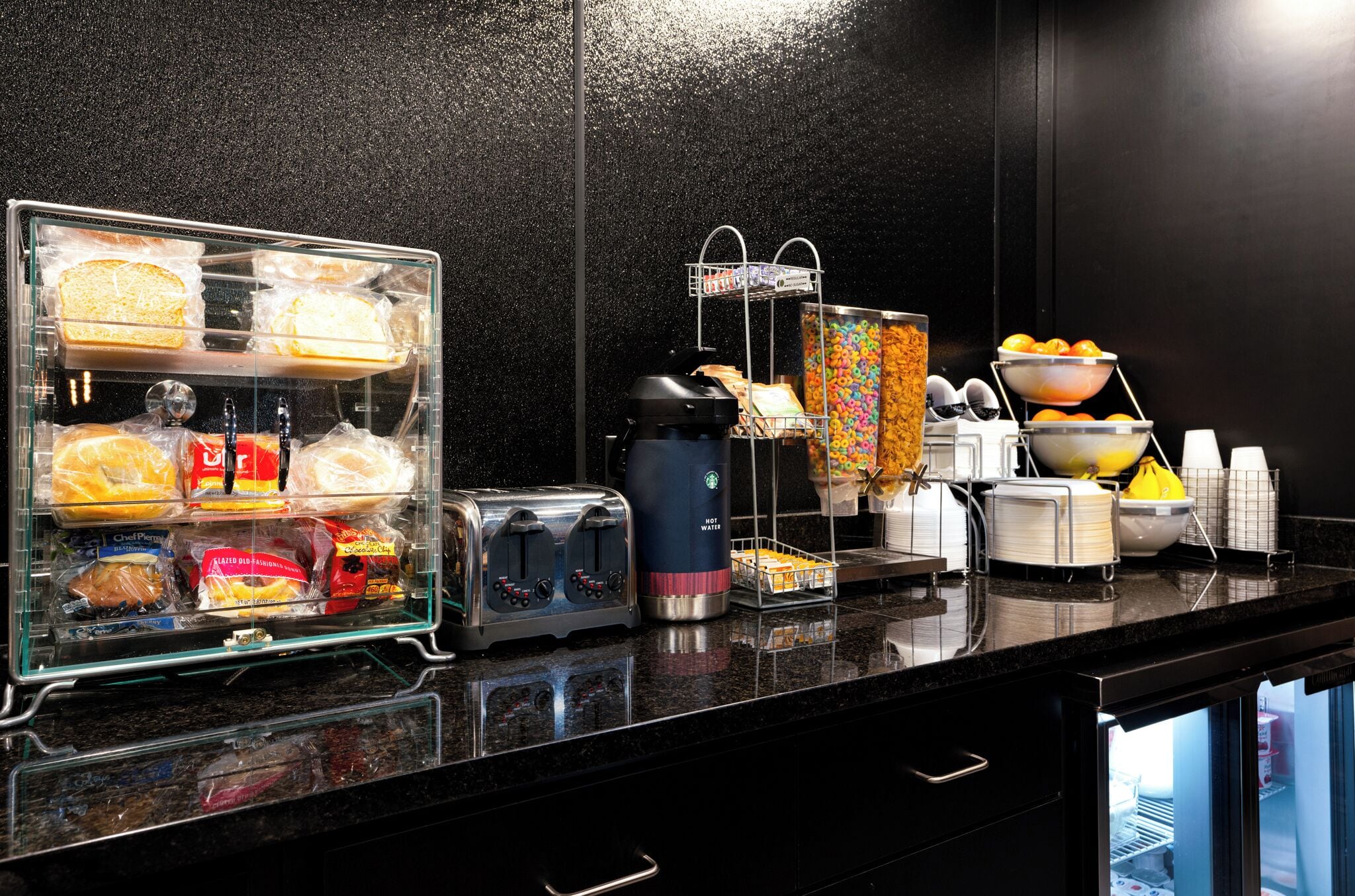 A breakfast buffet with various food items, a coffee machine, and a fruit bowl.